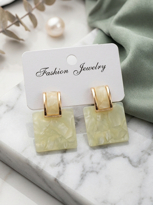 Butter yellow marble-effect square drop earrings with gold-tone rectangular tops on a jewellery display card.