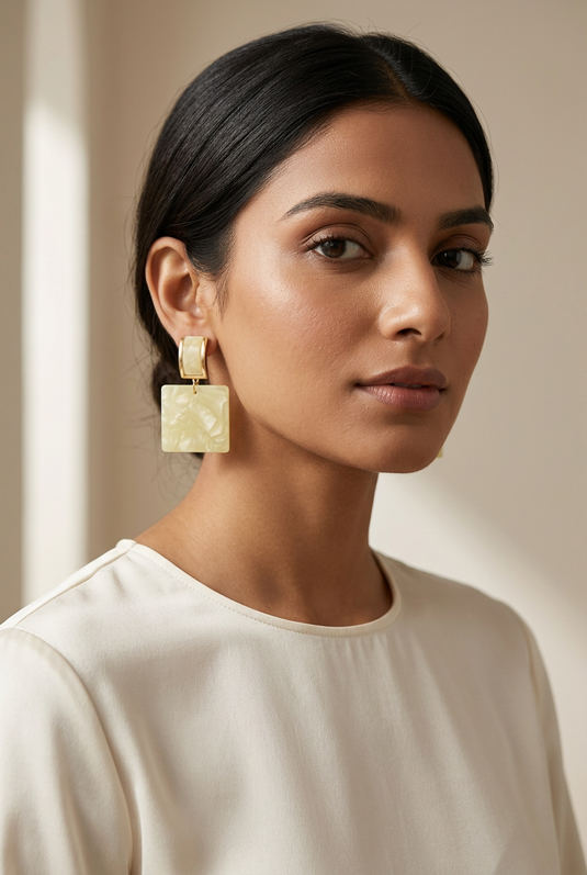 Woman in an ivory blouse wearing butter yellow marble-effect square drop earrings with gold-tone rectangular tops.