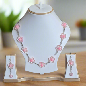 Necklace with pink flower pendants on a white stand with matching earrings.