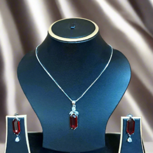 Elegant red ruby and CZ pendant set displayed on a black jewelry stand, featuring a silver-plated chain.