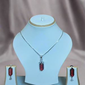Elegant Garimas pendant set featuring red ruby and CZ stones on a silver-plated chain, showcased on a jewelry display.