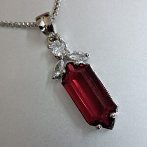 Elegant Garimas pendant set featuring a vibrant red ruby and CZ stones on a silver-plated chain.